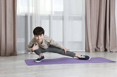 Küçük çocuk evde egzersiz yapıyor. Sabah rutini