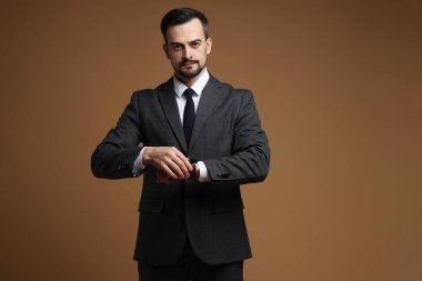 Klasik takım elbiseli adam kahverengi arkaplanı kontrol ediyor