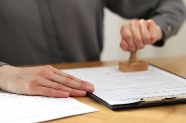 Kadın, ahşap masada lisans sözleşmesi imzalıyor, yakın plan.