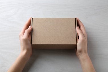 Beyaz ahşap arka planda boş karton kutusu olan kadın, yakın plan. Tasarım için model