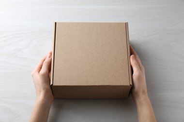 Beyaz ahşap arka planda boş karton kutusu olan kadın, yakın plan. Tasarım için model