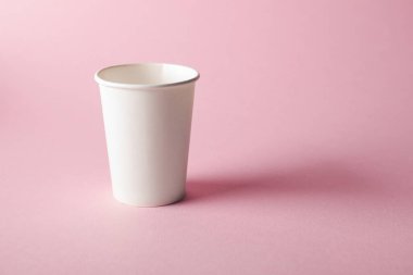 Pembe arka planda bir kağıt bardak. Tasarım için model