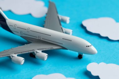 Açık mavi zemin üzerinde kağıt bulutlar arasında uçak modeli, yakın plan