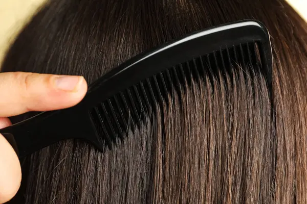 Saçlarını plastik tarak ile tarayan kadın, yakın plan.