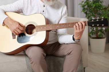 Rahatlatıcı hobi. Son sınıf öğrencisi evdeki kanepede gitar çalıyor, yakın plan.
