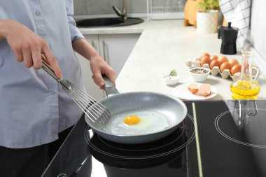 Kapalı mekanda ızgara tavada yumurta pişiren kadın, yakın plan.