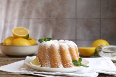 Pudra şekerli lezzetli limonlu pasta, taze meyve dilimi ve ahşap masada nane.