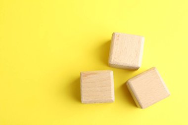 Sarı arka planda tahta küpler, düz yatış. Metin için boşluk