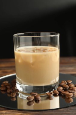 Bardakta kremalı kahve likörü ve ahşap masada fasulye, yakın plan.