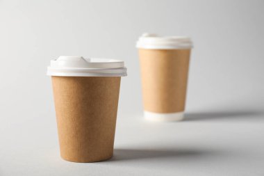 Gri arka planda kapaklı kağıt bardaklar, seçici odaklanma. Tasarım için model