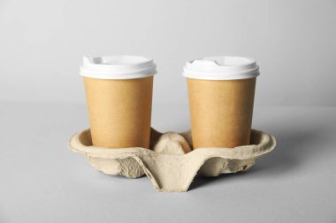 Gri arka planda kapaklı kağıt bardaklar, yakın plan. Tasarım için model