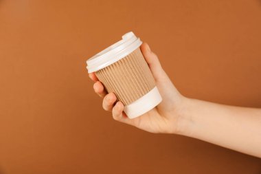 Kahverengi arka planda kağıt bardak tutan kadın, yakın plan. Tasarım için model