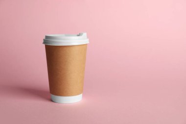 Pembe arka planda bir kağıt bardak. Tasarım için model