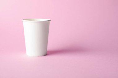 Pembe arka planda bir kağıt bardak. Tasarım için model