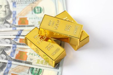 Parlak altın külçeler ve beyaz arka planda dolar banknotları, yakın plan