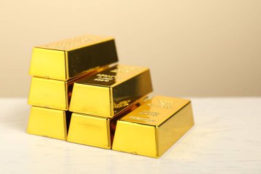 Bej arkaplan ile aydınlık masa üzerindeki altın külçeleri, yakın plan