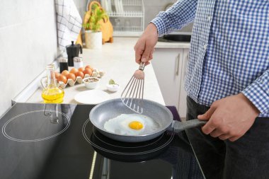 Kapalı mekanda tavada yumurta pişiren adam, yakın plan.