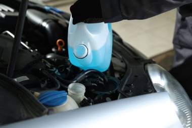 Plastik kutudan araba deposuna cam temizleyici döken adam, yakın plan.