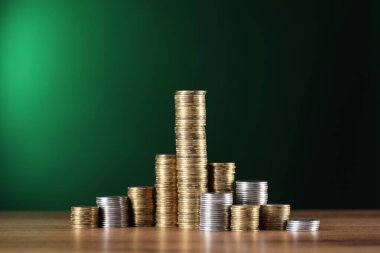 Ahşap masadaki para yığınları yeşil arka plana karşı, yakın plan