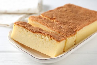 Tasty Japanese Castella sponge cake on white wooden table, closeup