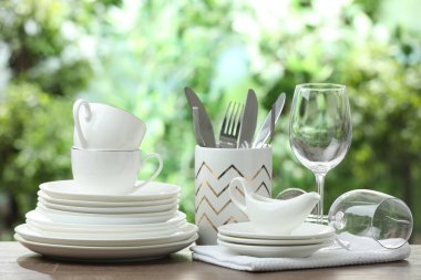 Clean dishware on wooden table against blurred background