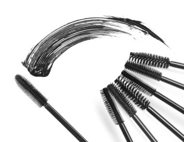 Maskara lekesi ve beyaz arka planda farklı fırçalar, üst manzara. Dekoratif kozmetik