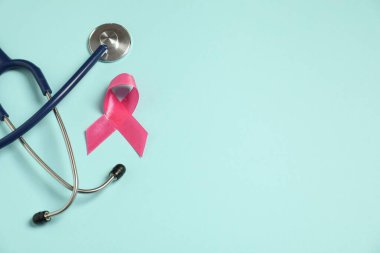 Göğüs kanseri farkındalığı. Açık mavi arka planda pembe kurdele ve steteskop. Metin için boşluk
