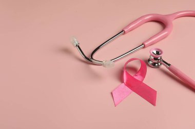 Göğüs kanseri farkındalığı. Renkli arka planda pembe kurdele ve steteskop, yakın plan. Metin için boşluk