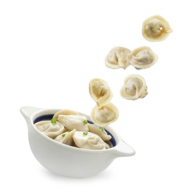 Lezzetli haşlanmış hamur tatlısı (pelmeni) beyaz arka planda kaseye düşüyor