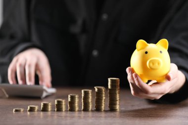 Kumbarası, hesap makinesi ve yığınla parası olan adam, yakın plan.