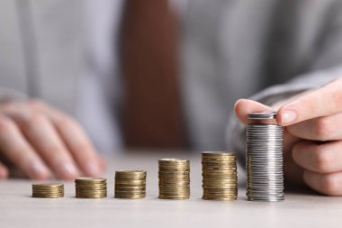 Beyaz ahşap masadaki bozuklukların üzerine para koyan adam, yakın plan.