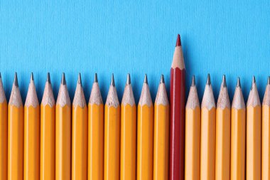 Açık mavi zemin üzerinde grafit olanlar arasında bir kırmızı kalem, üst görünüm