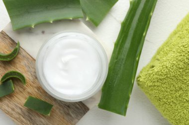 Beyaz desenli arka planda krema ve aloe yaprakları, düz yatıyordu