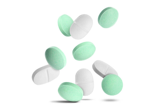 Много различных таблеток падает на белом фоне