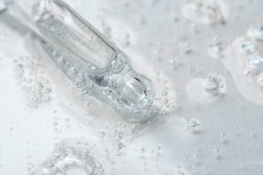 Işık arka planında kozmetik serumu olan bir boru, yakın plan.