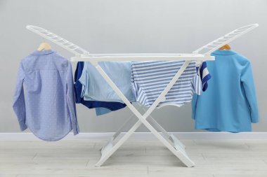 Gri duvarın yanında temiz çamaşırları olan kuru askı.