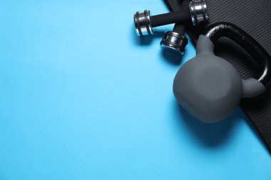 Kettlebell, minder ve halterler açık mavi arka planda, düz yerde. Metin için boşluk