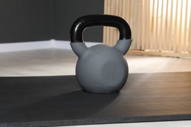 Jimnastik salonunda yerde bir tane kettlebell ve paspas.
