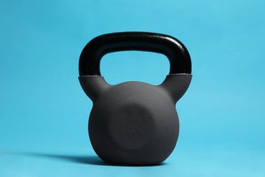 Açık mavi arka planda ağır bir kettlebell.