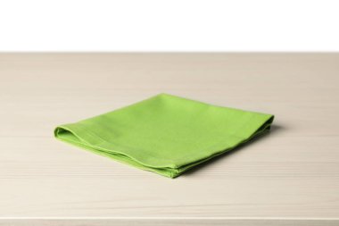 Beyaz arkaplana karşı açık ahşap masa üzerinde yeşil peçete