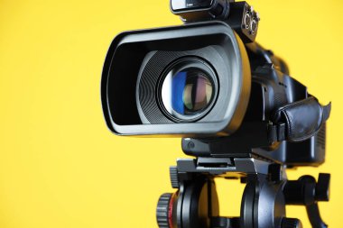 Sarı arka planda modern video kamera, yakın plan. Metin için boşluk