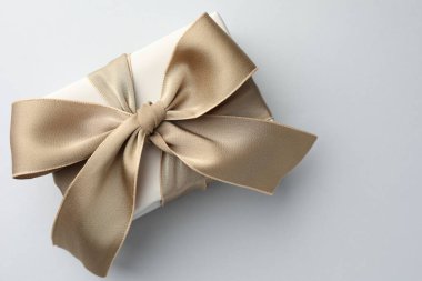 Işık arka planında güzel bir fiyonk olan hediye kutusu, üst manzara. Metin için boşluk