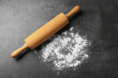 Gri masa üzerinde ahşap merdane ve un, üst manzara.