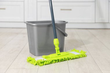 Kapalı alanda ahşap zeminde mikrofiber paspas ve kova.