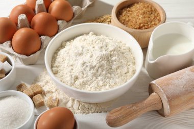 Hamur için merdane ve malzemeler beyaz ahşap masada, yakın plan.