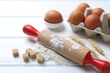 Yuvarlanan iğne, un, yumurta, küp şeker ve çiviler beyaz ahşap masada, yakın plan.