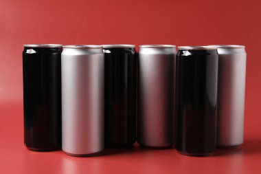 Kırmızı arka planda birçok alüminyum içecek kutusu