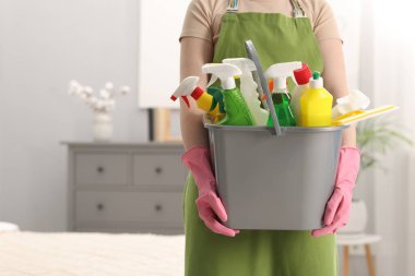 Evde bir kova temizlik malzemesi olan bir kadın, yakın çekim. Metin için boşluk