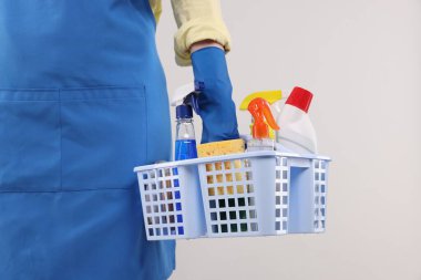 Arka planda temizlik malzemesi sepeti olan kadın, yakın plan.