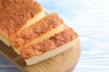 Açık mavi ahşap masada Japon Castella sünger keki kes, yakın plan. Metin için boşluk